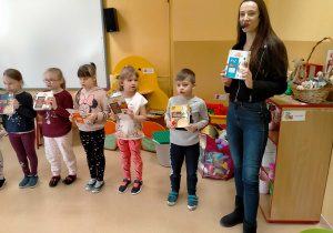 Dzieci stoją, trzymając w rękach pudełka po różnych kaszach i śpiewają piosenkę o kaszach z p.Agnieszką .